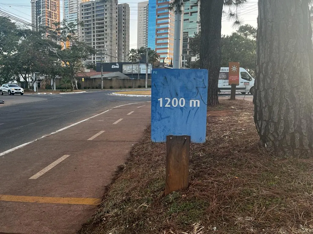 Uma placa no canteiro de uma pista de caminhada informando a distancia. 
