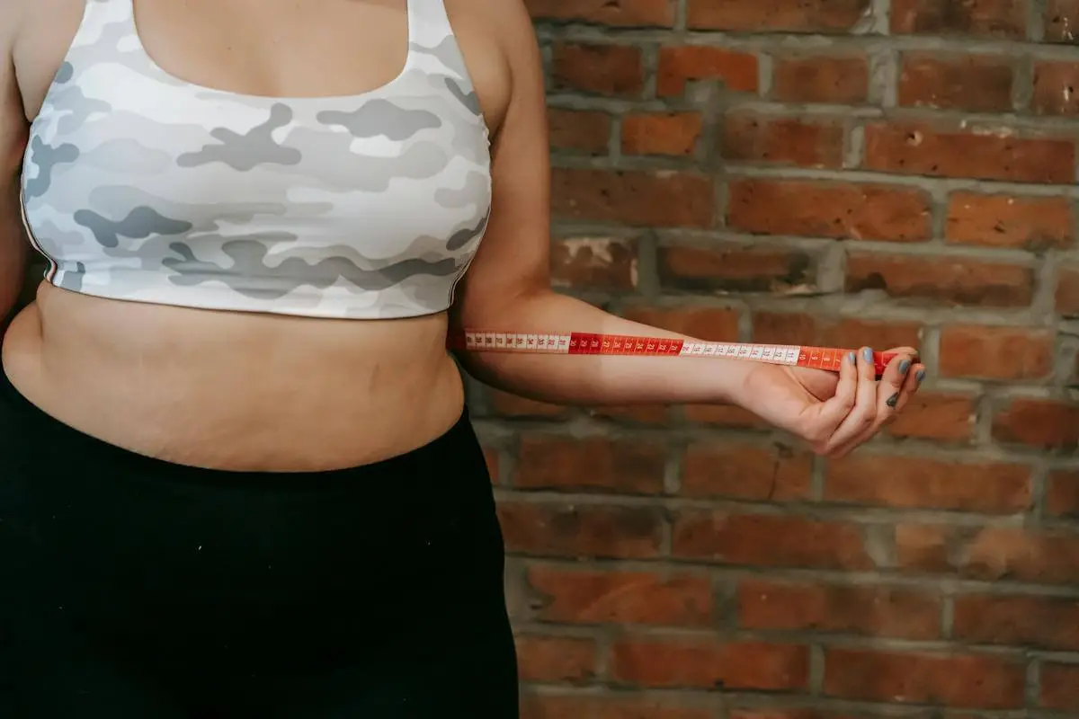 uma mulher segunda uma fita métrica medindo a circunferência abdominal e planejando perder barriga